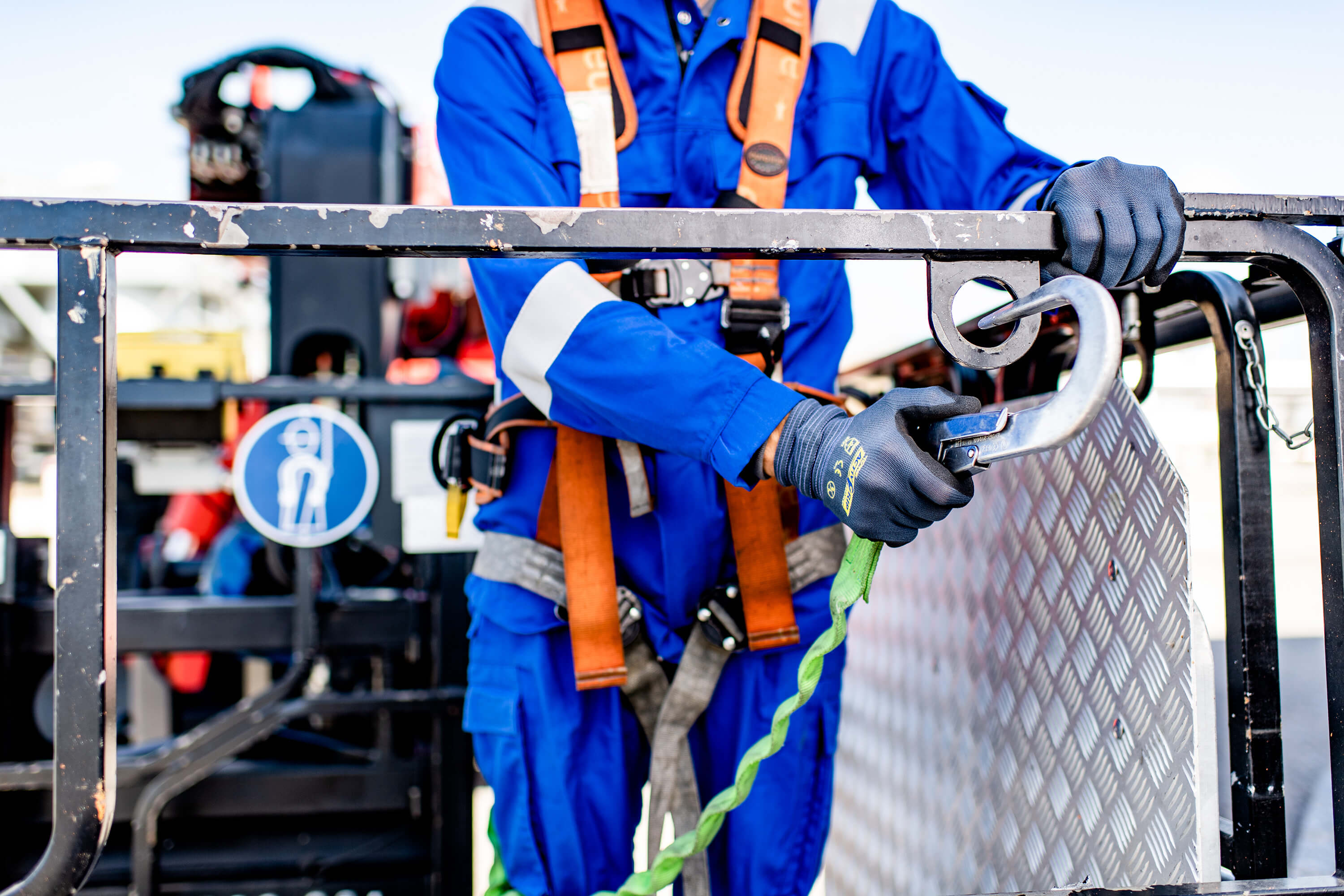 Nahaufnahme eines Mitarbeiters mit Arbeitskleidung und einem Sicherheitsgurt