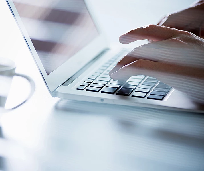 Nahaufnahme von Händen, die an einem Laptop tippen