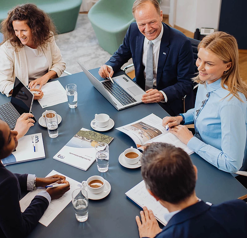 RAG Mitarbeiter*innen im Gespräch sitzen an einem Tisch mit Kaffee
