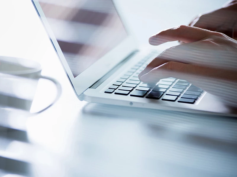 Nahaufnahme von Händen, die an einem Laptop tippen