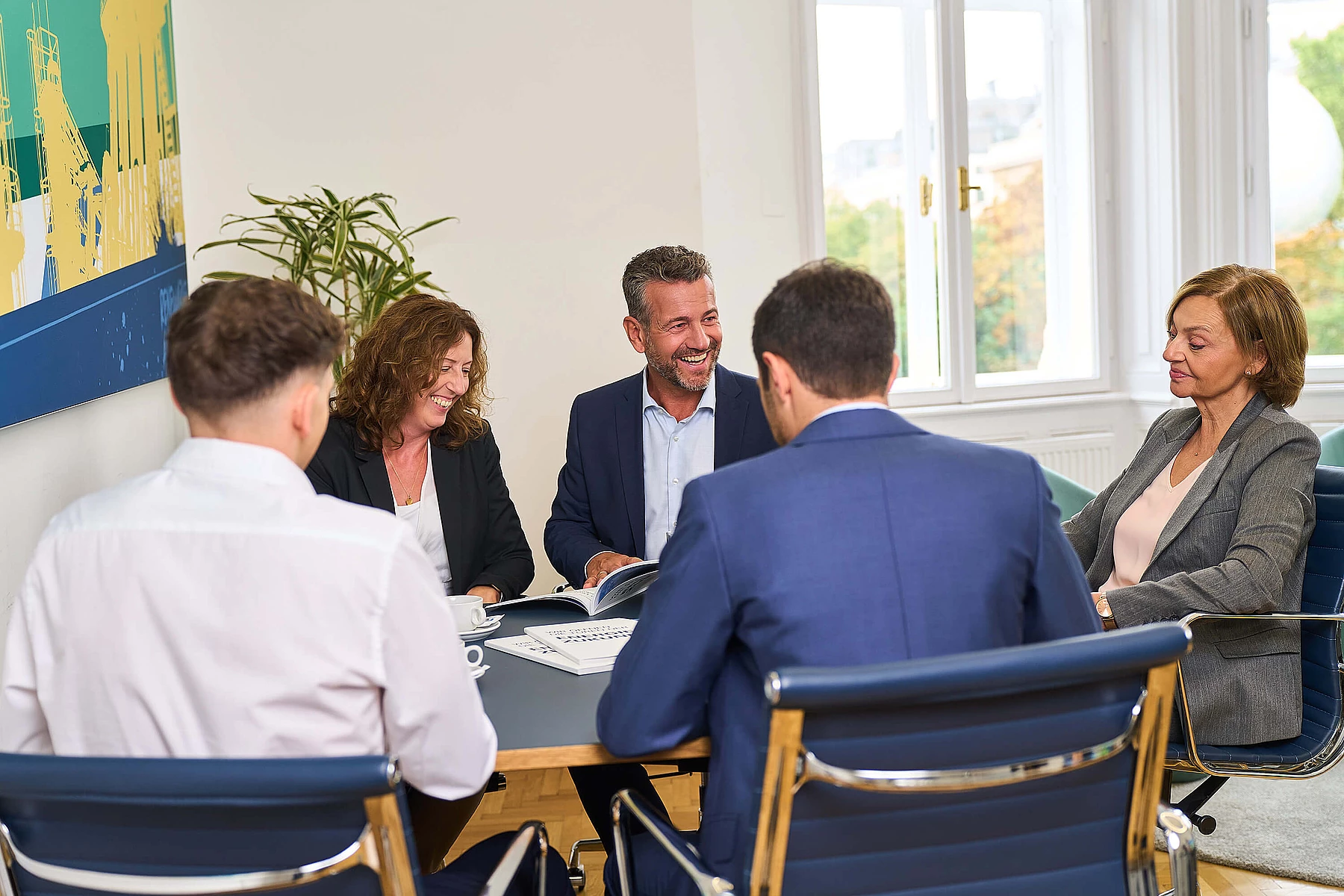 Mitarbeiterinnen und Mitarbeiter der RAG im Gespräch an einem Tisch im Büro