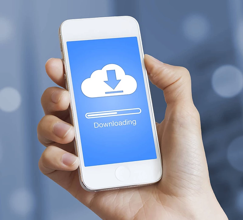 eine Hand hält ein Handy auf dem gerade etwas heruntergeladen wird