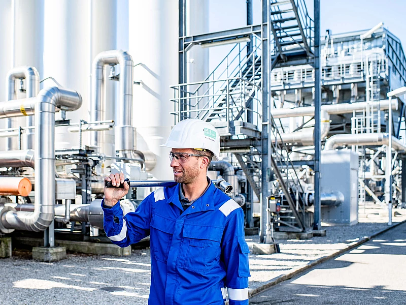 RAG Mitarbeiter in Arbeitskleidung mit Sicherheitsausrüstung vor einer Anlage